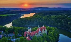 Malowniczy zamek otoczony lasami nad jeziorem, zachód słońca nad wzgórzami. Ten piękny most w Czechach wygląda jak z bajki.