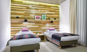 Dwa łóżka w nowoczesnym pokoju hotelowym z drewnianą ścianą. Idealne miejsce na nocleg, jeśli szukasz dobrych zamek janów podlaski opinie.