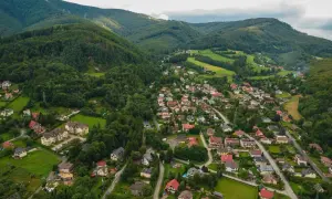 Malownicze uzdrowisko w Beskidzie Śląskim, z domami wciśniętymi między zielone wzgórza i lasy.