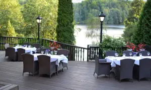 Elegancki taras z nakrytymi stołami i widokiem na jezioro. Idealne miejsce na relaks w spa na Mazurach.