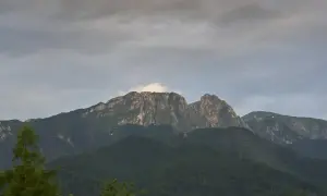 Giewont, śpiący rycerz Tatr, w chmurach. Góry o skalistych zboczach, porośnięte lasem.