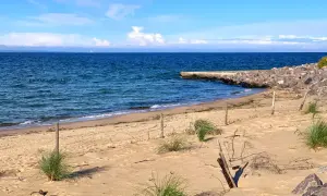 Plaża na półwyspie Św. Wawrzyńca z kamiennym falochronem i błękitnym morzem.