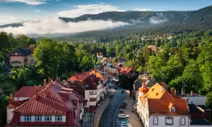 Widok na malowniczy rynek w Szklarskiej Porębie z czerwonymi dachami i otaczającymi go zielonymi wzgórzami Karkonoszy.