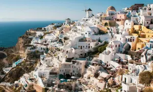 Malownicze białe domy Santorini, w tym wiatraki, wznoszą się na klifie nad morzem. Widok przypomina starożytne Akrotiri.