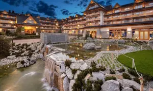 Elegancki hotel spa w górach z kaskadą wodną i stawem.