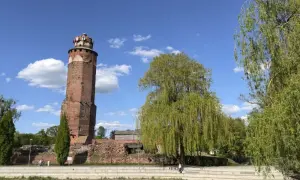 Wieża zamkowa w Brodnicy, otoczona zielenią, na tle błękitnego nieba z chmurami. Piękny dzień na Pojezierzu Brodnickim.