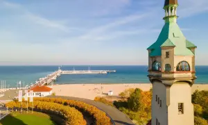 Widok na latarnię morską w Sopocie, plażę i molo w jesienny, słoneczny dzień.