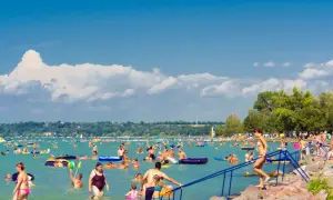 Tłum ludzi cieszy się latem na **jeziorze Balaton**. Kąpiel, pływanie na materacach i relaks na plaży.