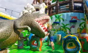 Chłopiec skacze na dmuchanym dinozaurze. Wspaniałe, ciekawe miejsca do 100 km od Katowic dla dzieci.