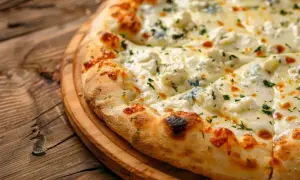 Pyszna pizza z czterema serami, w tym kremową **mozzarellą**, na drewnianej desce.
