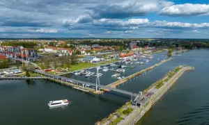Widok na jezioro, nad którym leży Giżycko, z mariną pełną łodzi, nowoczesnym mostem i spacerowiczami.