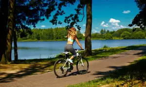 Kobieta na rowerze podziwia malownicze **trasy rowerowe Mazury** nad jeziorem.