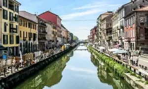 Malownicze Navigli w Mediolanie, z kolorowymi kamienicami po obu stronach kanału, odbijającymi się w wodzie.