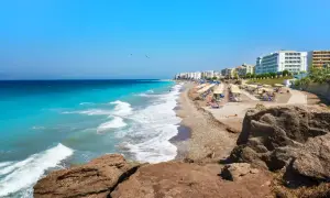 Słoneczna plaża na Rodos, z turkusową wodą i rzędami leżaków. To jedno z najpiękniejszych miejsc na wyspie, idealne na relaks.