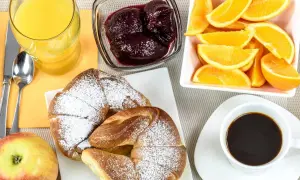 Idealne śniadanie kontynentalne: świeże croissanty, sok pomarańczowy, kawa, owoce i dżem.