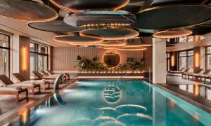 Luksusowy basen w karpacz hotel spa. Woda lśni, otoczona leżakami i zielenią. Nowoczesny design sufitu z podświetleniem.