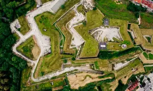 Widok z lotu ptaka na Twierdzę Kłodzko, imponującą budowlę obronną o charakterystycznym kształcie gwiazdy, otoczoną zielenią.