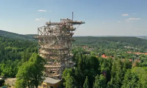 Wieża widokowa w Szklarskiej Porębie, przypominająca spiralny deptak, wznosi się nad zielonymi lasami i miastem.