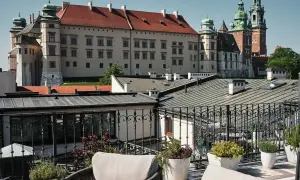 Widok z tarasu krakowskiego hotelu spa na Wawel. Wygodne fotele i rośliny tworzą relaksującą atmosferę.