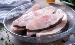 Świeże kawałki halibuta ryby w szklanej misce, gotowe do przygotowania.