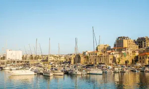 Port w Heraklionie, stolicy Krety, pełen żaglówek i jachtów. W tle zabytkowe mury i nowoczesne budynki.