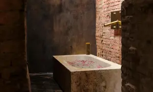 Kamienna wanna z płatkami róż i świecą, w łazience z ceglaną ścianą.
