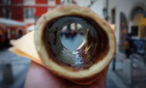 Trdelník z czekoladą, jeden z pysznych czeskich przysmaków, widziany przez jego wnętrze na tle ulicy.