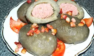 Cepelin z mięsem, okraszone skwarkami i pomidorem, wyglądają apetycznie.