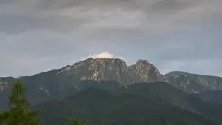 Giewont, śpiący rycerz Tatr, w chmurach. Góry o skalistych zboczach, porośnięte lasem.
