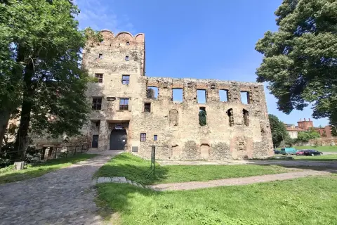 Kamienne mury i wieża zamku w Ząbkowicach Śląskich, otoczone zielenią, zapraszają do odkrywania historii.