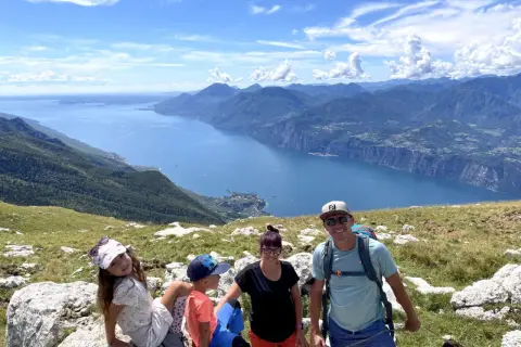 Rodzina z psem cieszy się widokiem na jezioro Garda z Monte Baldo.