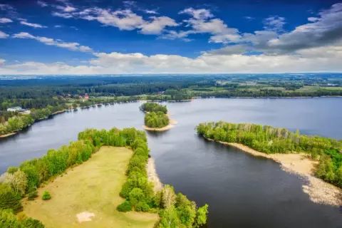 Malownicze wyspy na bałtyku, otoczone ciemną wodą i bujną zielenią lasów, pod błękitnym niebem z chmurami.
