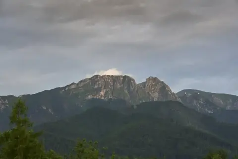 Giewont, śpiący rycerz Tatr, w chmurach. Góry o skalistych zboczach, porośnięte lasem.