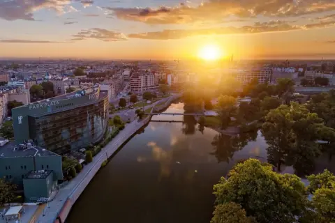 Zachód słońca nad Odrą we Wrocławiu, idealny na city break. Widok na Park Plaza i malownicze kamienice.