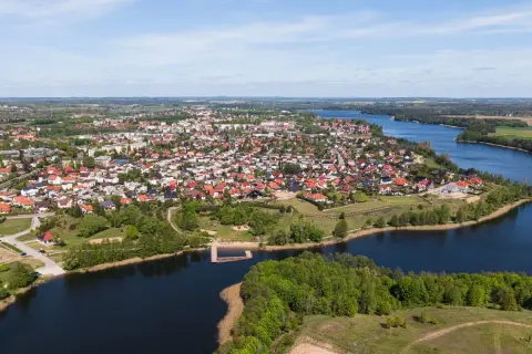 Widok z lotu ptaka na miasteczko nad jeziorem, z dachami domów i zielenią. To największy rynek w Polsce, tętniący życiem.