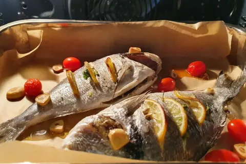 Dwie dorady pieczone z cytryną, czosnkiem i pomidorkami. Dorada co to za ryba? Pyszna ryba prosto z pieca!