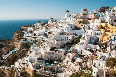 Malownicze białe domy Santorini, w tym wiatraki, wznoszą się na klifie nad morzem. Widok przypomina starożytne Akrotiri.