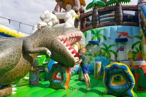 Chłopiec skacze na dmuchanym dinozaurze. Wspaniałe, ciekawe miejsca do 100 km od Katowic dla dzieci.