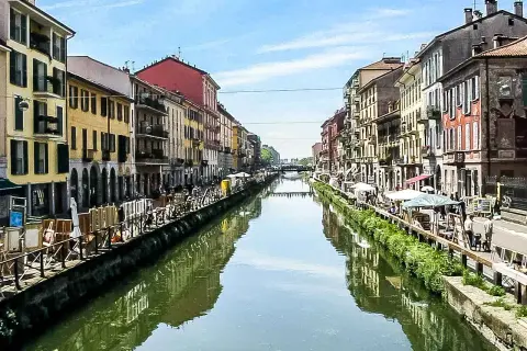 Malownicze Navigli w Mediolanie, z kolorowymi kamienicami po obu stronach kanału, odbijającymi się w wodzie.