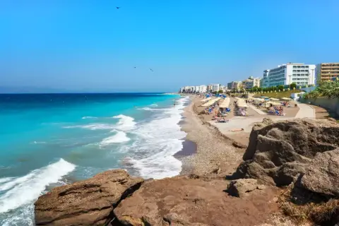 Słoneczna plaża na Rodos, z turkusową wodą i rzędami leżaków. To jedno z najpiękniejszych miejsc na wyspie, idealne na relaks.