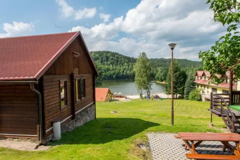 Drewniane domki nad jeziorem w Dolnośląskim, z placem zabaw i widokiem na las.