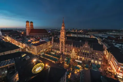 Nocny jarmark bożonarodzeniowy w Monachium. Widać Nowy Ratusz, Frauenkirche i rozświetlone stragany.