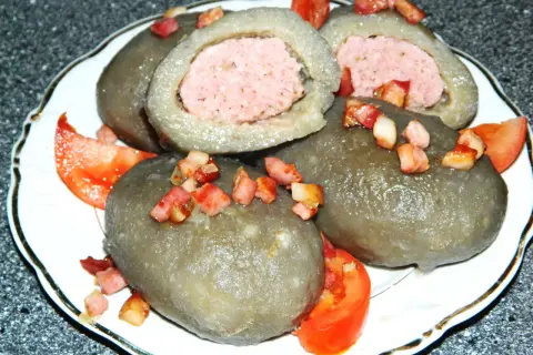 Cepelin z mięsem, okraszone skwarkami i pomidorem, wyglądają apetycznie.