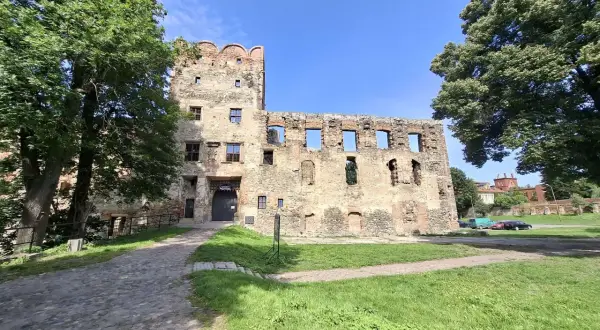 Kamienne mury i wieża zamku w Ząbkowicach Śląskich, otoczone zielenią, zapraszają do odkrywania historii.