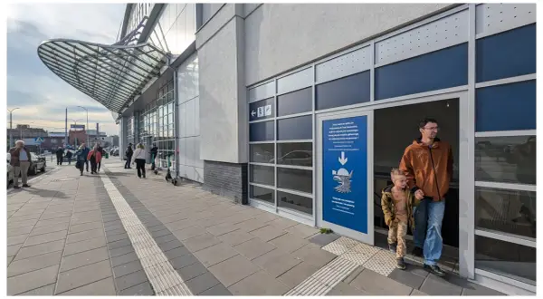Ojciec z synem wchodzą do Podziemnych Tras Szczecina. Na zewnątrz ruchliwy rynek Szczecin.
