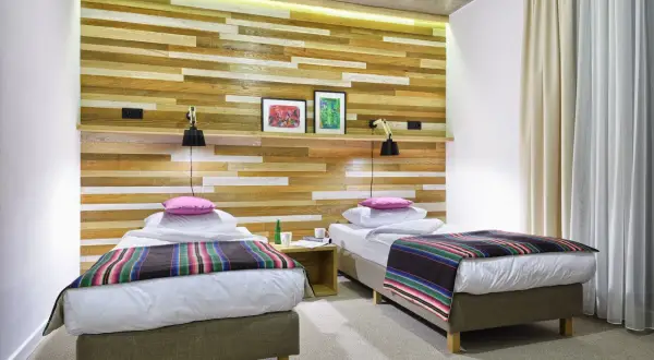 Dwa łóżka w nowoczesnym pokoju hotelowym z drewnianą ścianą. Idealne miejsce na nocleg, jeśli szukasz dobrych zamek janów podlaski opinie.
