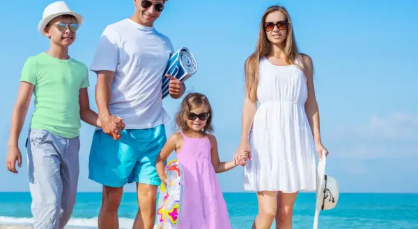 Rodzina cieszy się wakacjami w Polsce z dziećmi nad morzem. Słońce, plaża i uśmiechy na twarzach.
