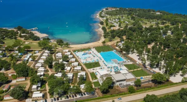 Idealne miejsce, gdzie na wakacje z dziećmi: kompleks basenów, plaża i domki w otoczeniu zieleni.