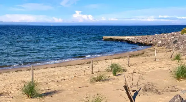 Plaża na półwyspie Św. Wawrzyńca z kamiennym falochronem i błękitnym morzem.