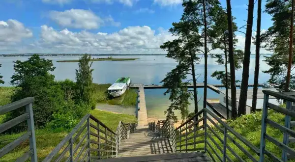 Schody prowadzą do jeziora, gdzie cumuje statek. To widok, który mówi "gdzie są Mazury".